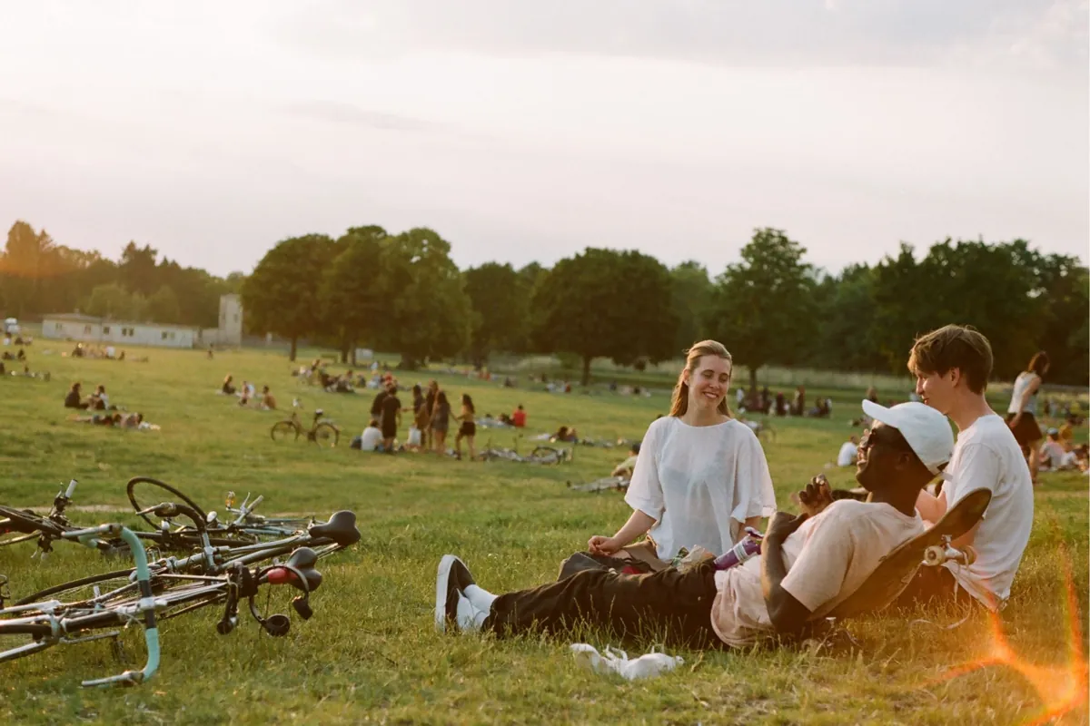 Three people relaxing on the grass beside their bicycles in a park