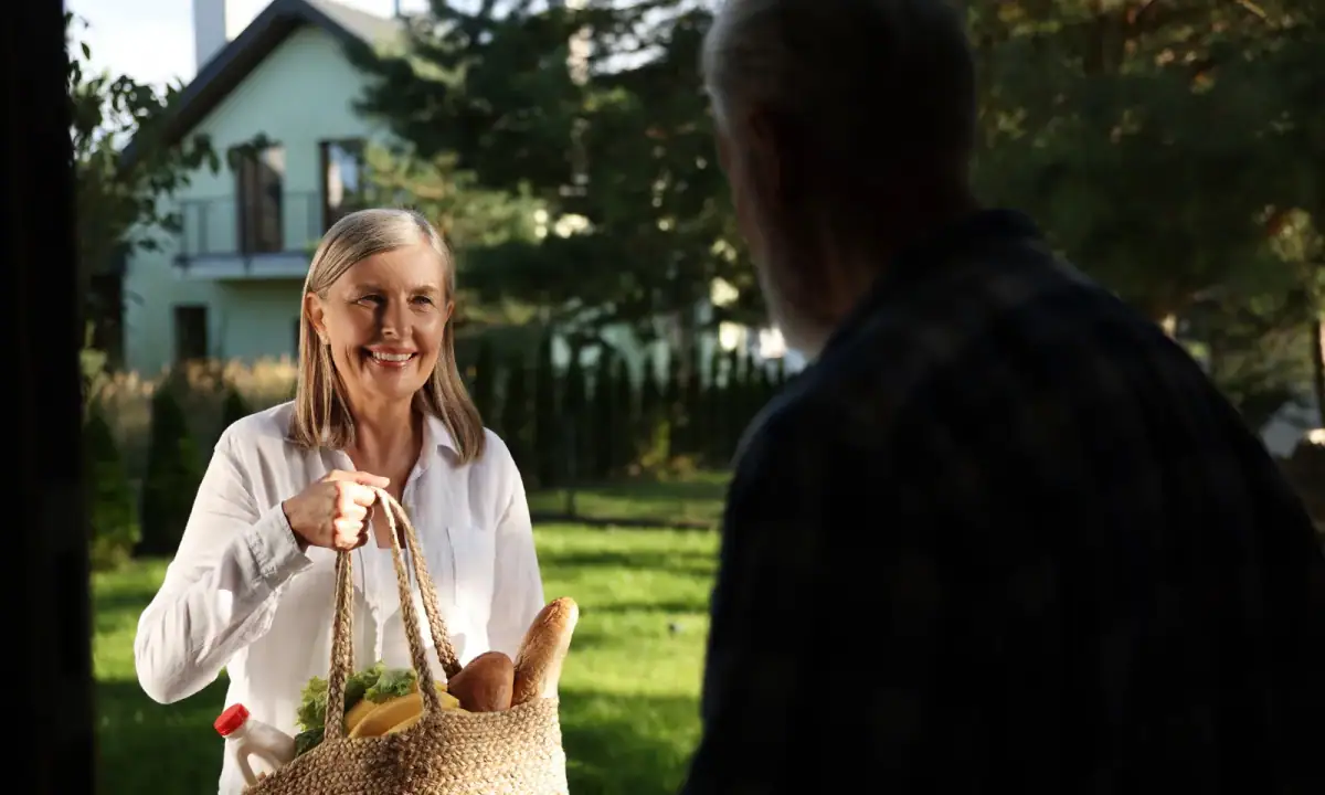 A neighbor bringing a basket of groceries to another neighbor