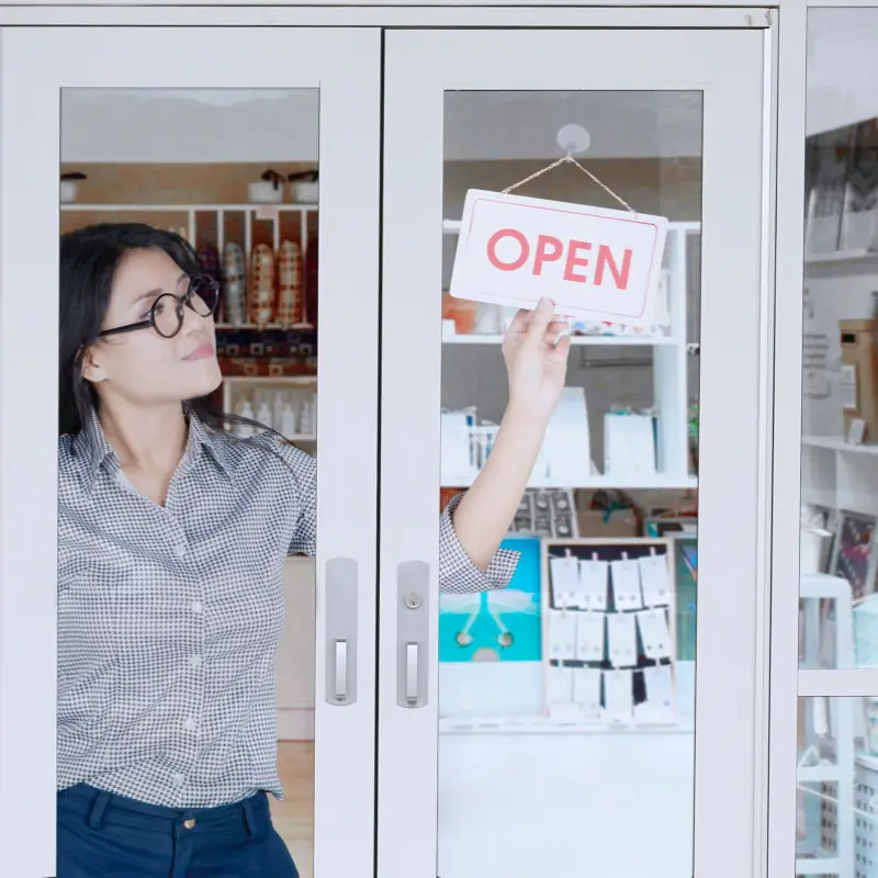 A small business owner turning the open sign at her shop