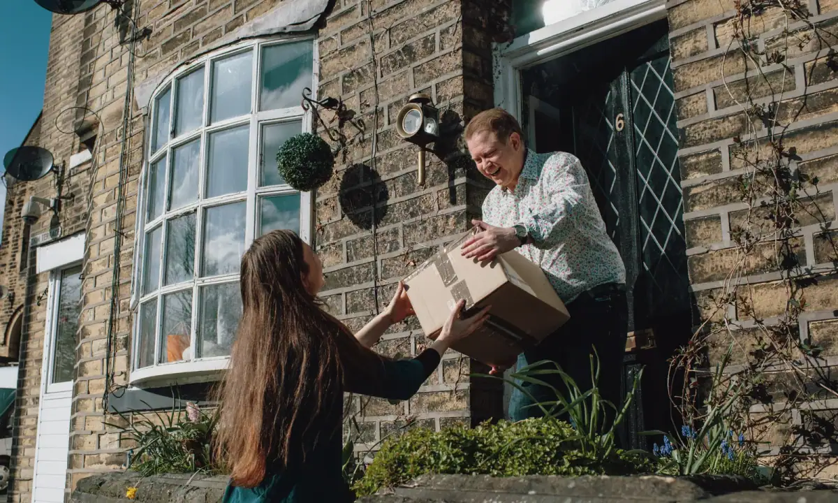 Neighbors helping one another carry a package