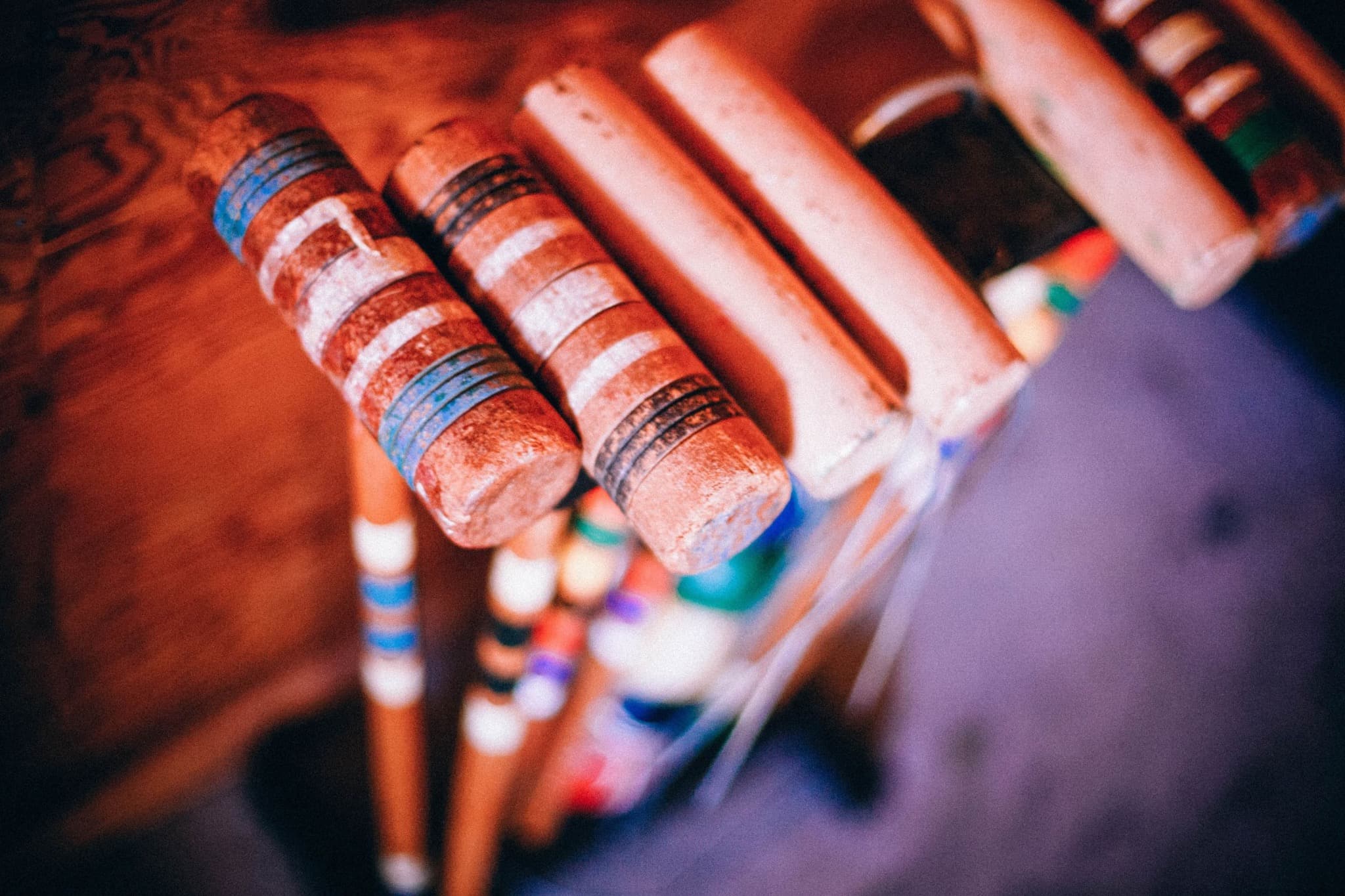Worn wooden croquet mallets arranged in a rack.