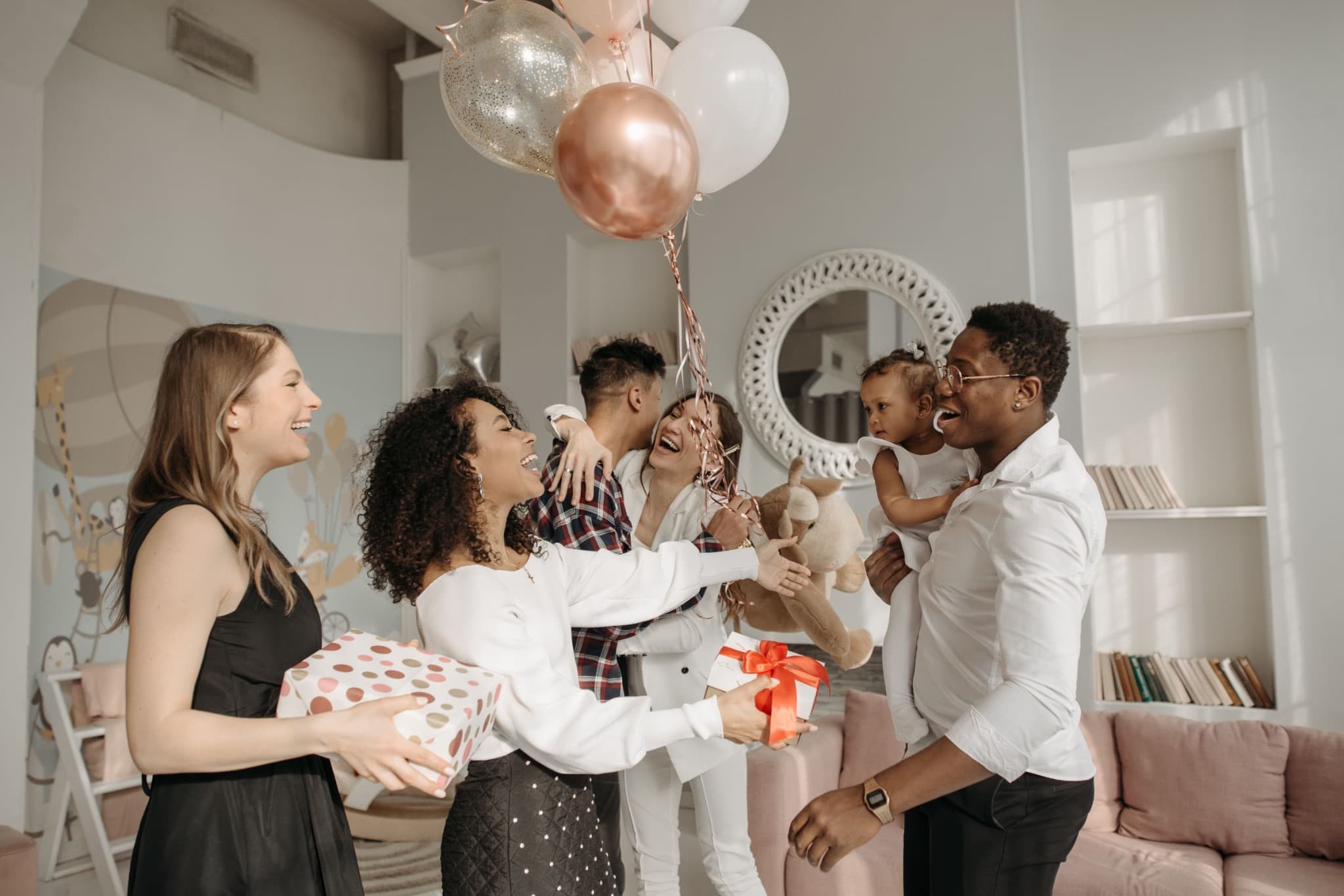 A small group smiling together at a celebration with balloons and gifts.