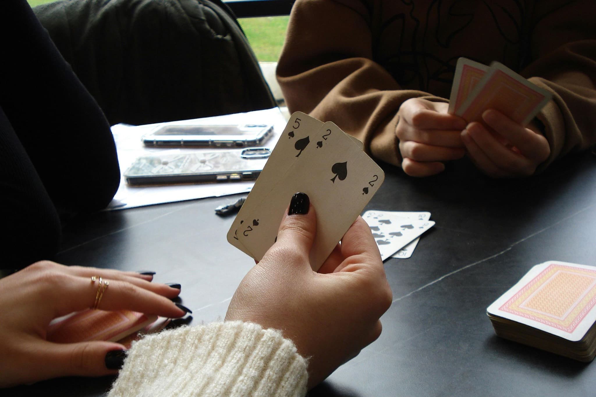 A player holding the five and two of spades during a card game.