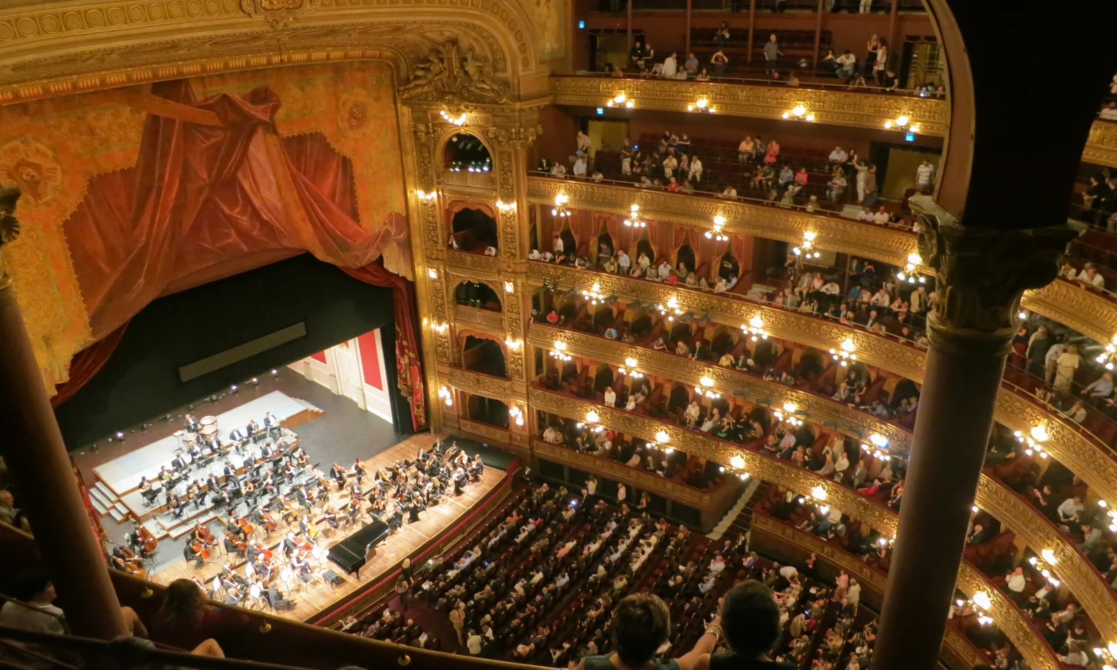 An audience overlooking an orchestra performing in a theatre.