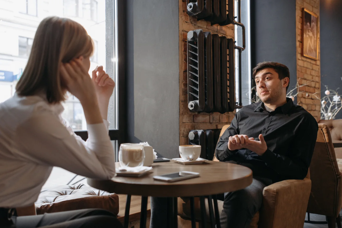 Two people talking over coffee at a café table.